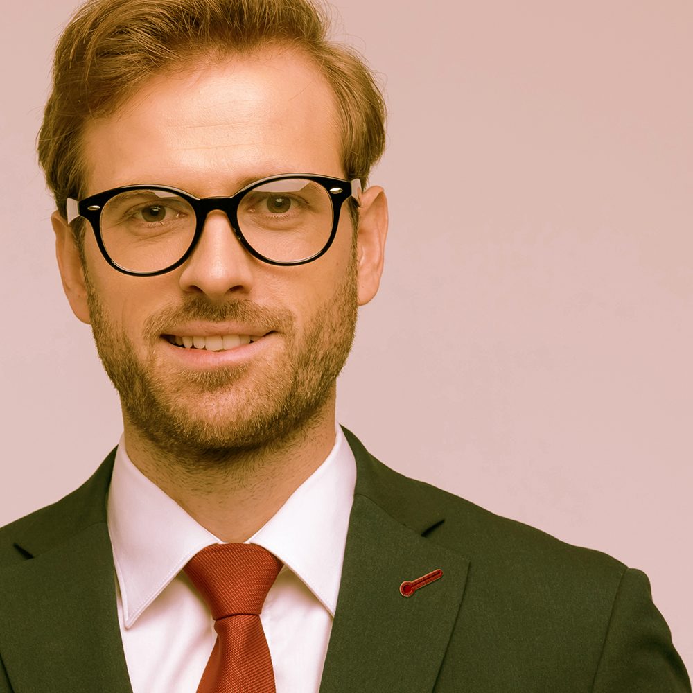Man in a green suit wearing a red Jacket Pop pin in his lapel