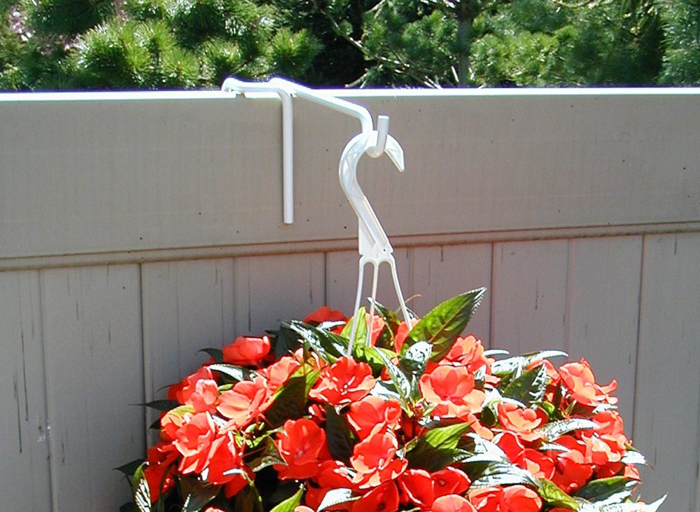 PFA vinyl fence hanger on top of a fence rail holding a hanging basket of red impatiens